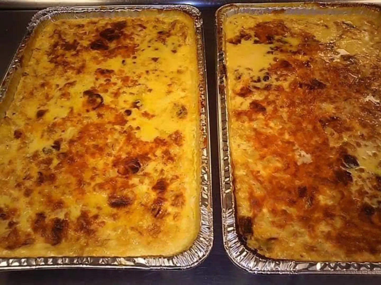 Two large trays of a golden baked comfort-food dish