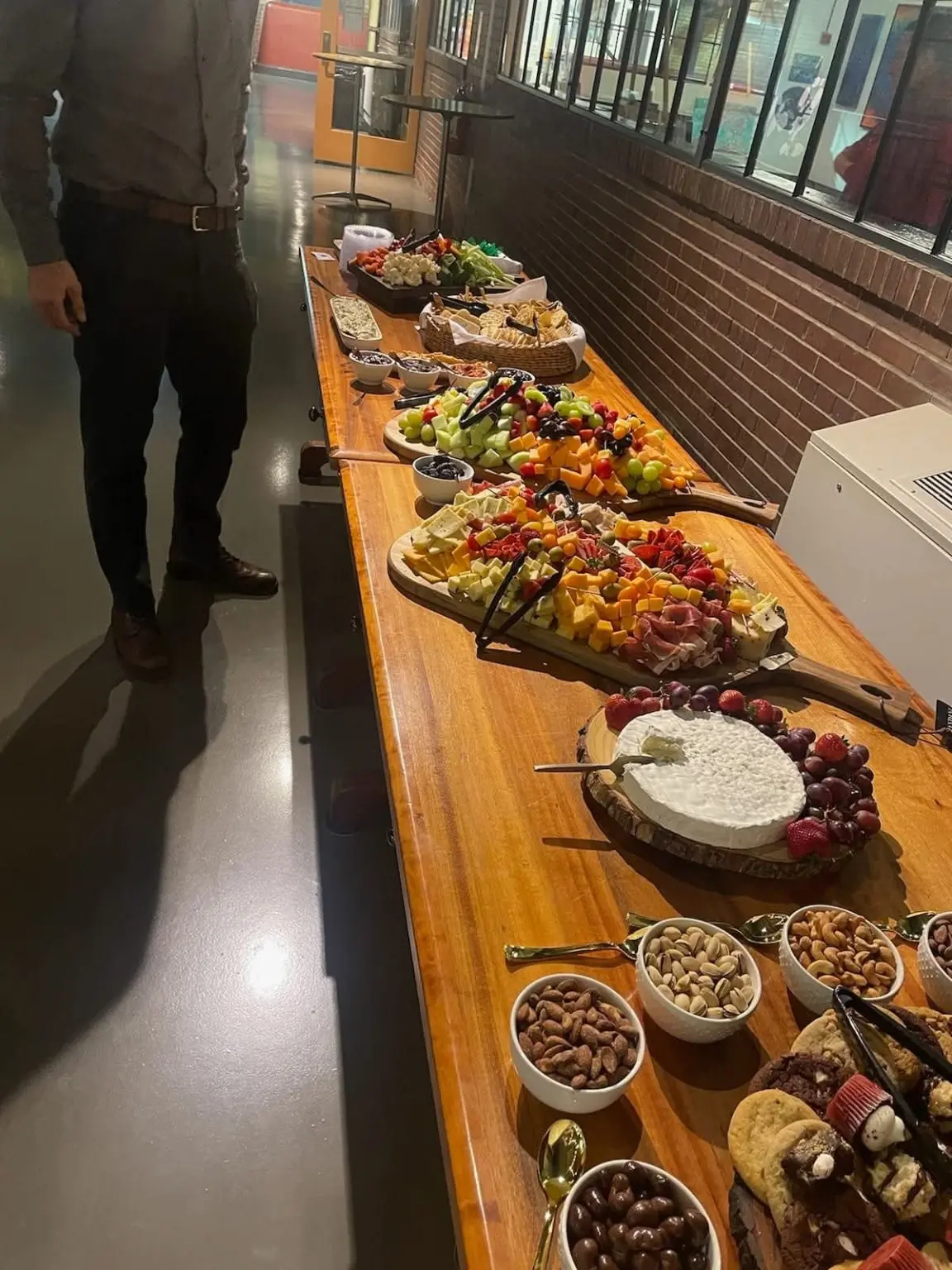 A long catering table arranged with fruit, cheese, crackers, dips, nuts, and desserts